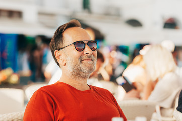 Outdoor portrait of 50 year old man wearing red t-shirt and sunglasses