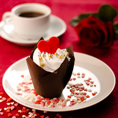 Valentine cupcakes decorated with sweet hearts on wooden table on a red background