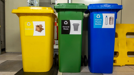 Yellow green and blue recycle wheelie bins in a plant room