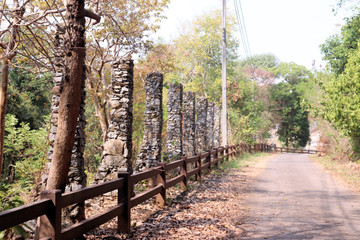 Crafted stone structure on roadside with young teak tree in background Thailand