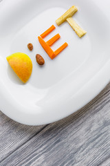 fruit on a plate of of apple, kiwi, carrots, nuts