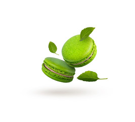 Green macaroons are flying on a white background. Beautiful bright macaroons with mint leaves