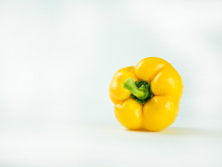 Yellow sweet bell pepper with water droplets on a white background.