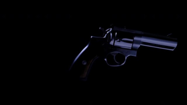 ISOLATED .357 HANDGUN ROTATING AS IT FLOATS IN DARKNESS.  ECU IN 4K, 10 BIT, 4:2:2.  NO PEOPLE.