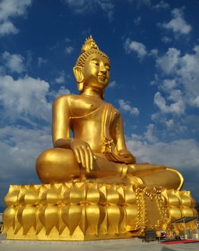 Big golden buddha statue, couldy sky. Norhern Thailand