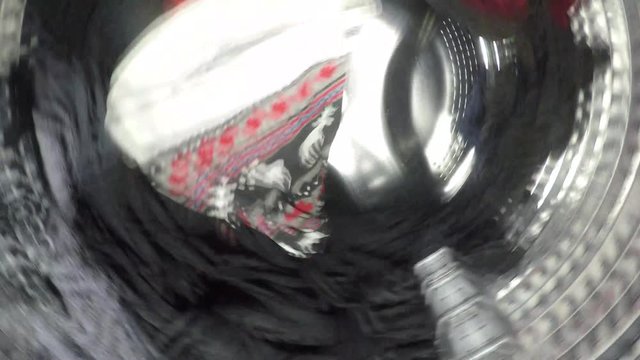 Unique perspective video of colorful clothes being washed, rinse and spin inside of the drum of the washer