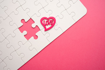 Valentines day copy space. Pink and red Heart shape beads on pink background with cutout puzzle. 