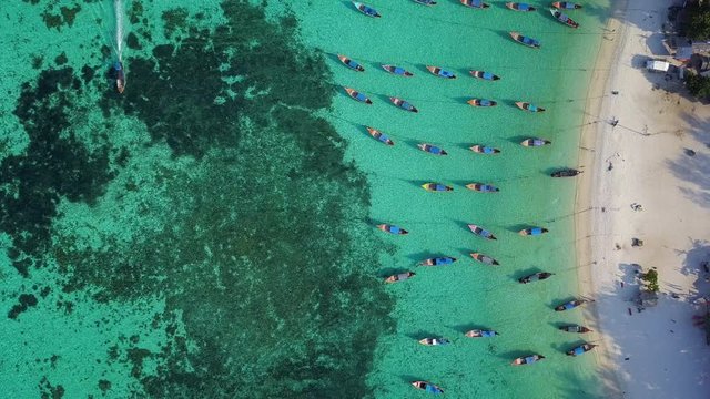 Aerial view, Summer colorful seascape with boats and tropical beach. Beautiful paradise in sandy seaside. Peaceful andaman sea at Koh Lipe, Satun, Thailand. Movement camera is zoom out.