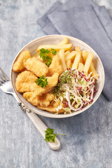 Chicken nuggets with raw salad and french fries on bright wooden background. Copy space. 