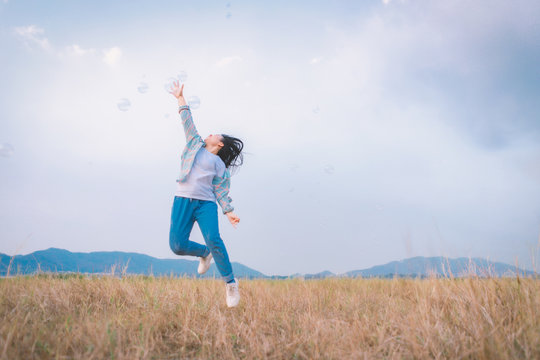 Blurry image of Happy young girl jumping with a Bubble on meadow in nature.