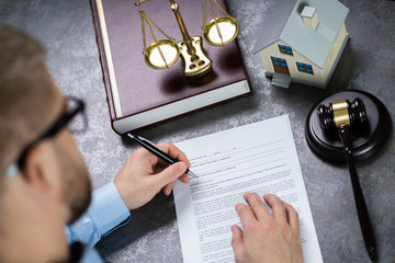 Judge With House Model Writing On Paper
