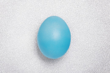 Easter Blue shine egg a silver glitter background. Holiday concept. Flat lay.