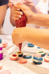 Obraz na płótnie Canvas Bunte Macarons mit leckerer Frucht und Knusper Karamell Creme gefüllt Dekoriert mit essbaren Blüten und Glitzerpuder