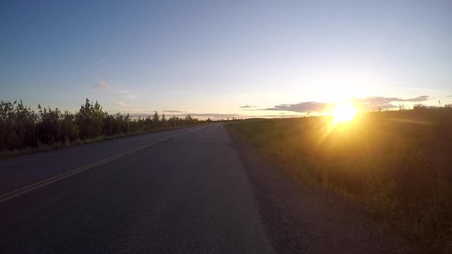 Driving towards the sunset in Alaska at a bumby road