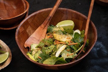 Avocado, apple slices and spinach salad in wooden bowl
