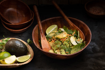 Avocado, apple slices and spinach salad in wooden bowl
