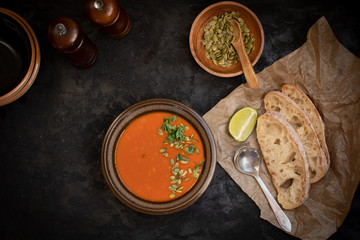 Vegan roasted pepper and tomato soup along with chiabatta bread on dark backround