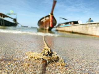 close up of rope for tie boat on blurry Longtail boat parked to wait for tourists at Ao Nang  beach, Thailand.