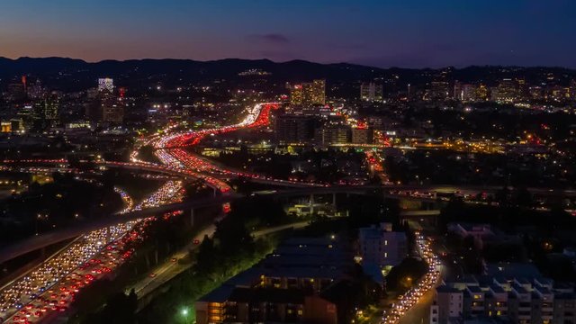 Aerial view of freeway and interstate street traffic during rush hour on the I-405 and I-10 in urban Los Angeles California with cars and car lights below at night.
