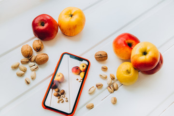 Shooting healthy food content on a smartphone. Man's hand holds a smartphone takes off fruits and nuts. The concept of a healthy lifestyle, proper nutrition, organic food. Raw food diet. Veganism 