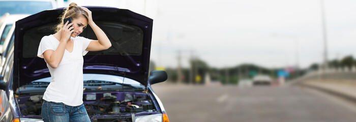 Woman Using Mobile Phone While Looking At Broken Down Car