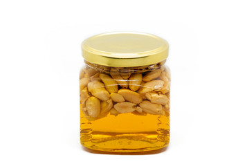 Glass jar with honey and peanuts on white background