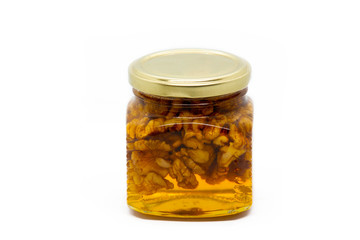 Glass jar with honey and walnuts on white background