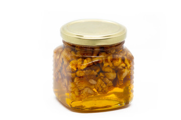 Glass jar with honey and walnuts on white background