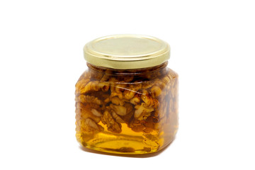 Glass jar with honey and walnuts on white background