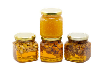 Pyramid of glass jars with honey with nuts and lemon on white background