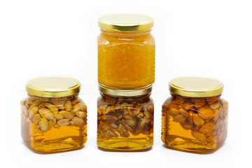 Pyramid of glass jars with honey with nuts and lemon on white background