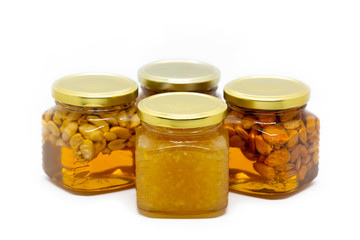 Pyramid of glass jars with honey with nuts and lemon on white background