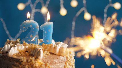 Birthday cake with 21 number candles and burning sparkler on blue backgraund. Close-up