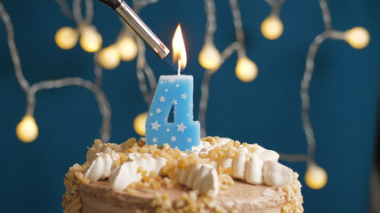 Birthday cake with 4 number candle on blue backgraund set on fire by lighter. Close-up