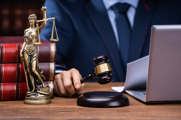 Judge Striking Gavel Near Mallet And Laptop