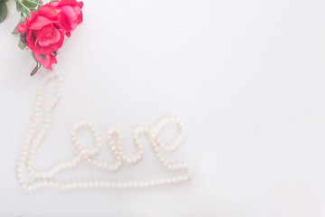 red roses and the inscription with beads love on a white background. concept of international women's day, spring, March 8, birthday