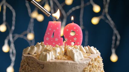 Birthday cake with 49 number candle on blue backgraund set on fire by lighter. Close-up view