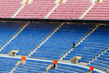 Empty stands of a stadium with empty seats of blue and red, and a maintenance person © lduarte
