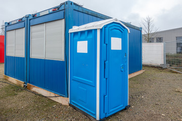 a construction site a blue construction site toilet stands next to a blue container