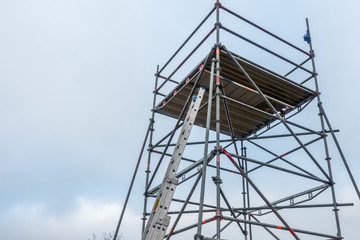 man climbs onto scaffolding on an extension ladder