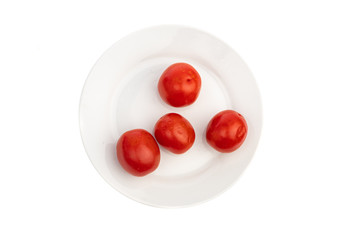 four pickled red tomatoes on a white plate isolated