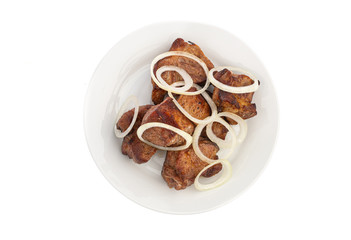 Skewers in large pieces of pork meat with onions on a white plate isolated