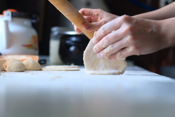 women's hands roll out the dough for dumplings