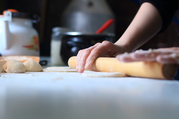 women's hands roll out the dough for dumplings
