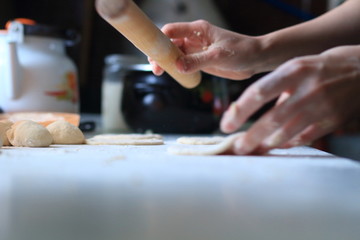 Fototapeta na wymiar women's hands roll out the dough for dumplings