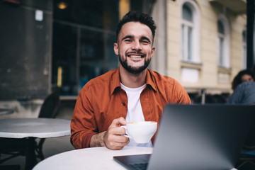 Laughing guy drinking coffee in street cafe