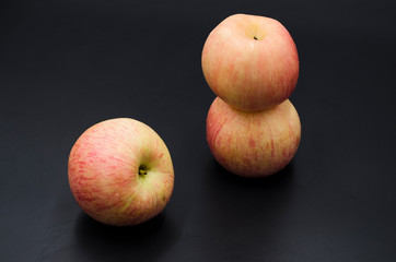 Three red apples on black background