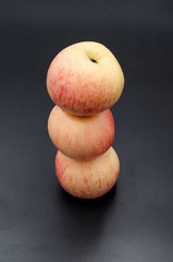 Three red apples on black background