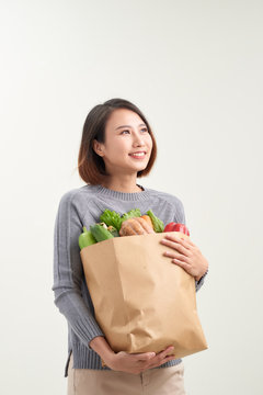 Horizontal orientation color image of a woman holding a paper bag overflowing with vegetables / Adding Veggies to your Diet