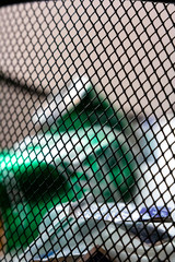 Close up of a trash can's metal mesh with blurred trash in the background